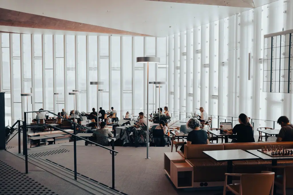Lyst, moderne bibliotek i Oslo der voksne sitter og leser og studerer